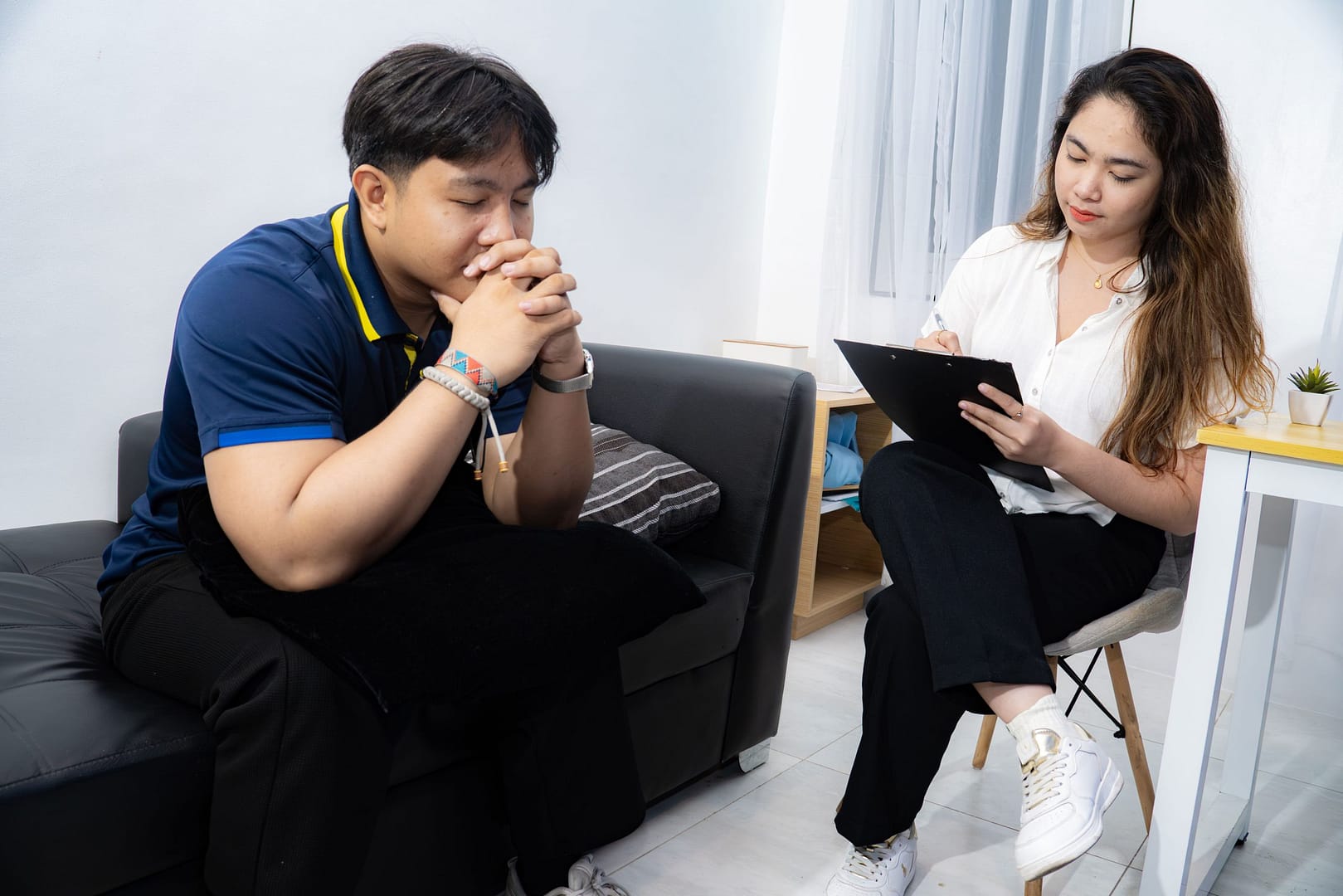 A GWI counselor takes notes while a client sits in quiet reflection during a session