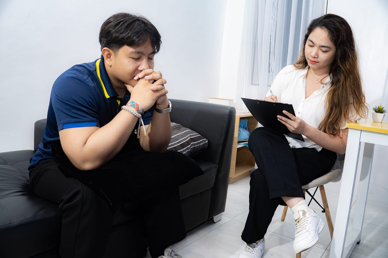 A GWI counselor takes notes while listening to a client during a one-on-one session