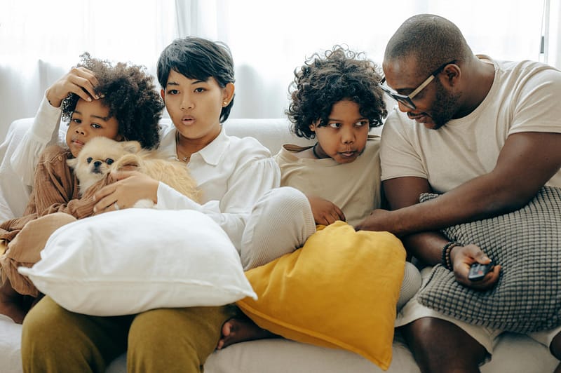 A multigenerational family relaxing together on a couch with their dog