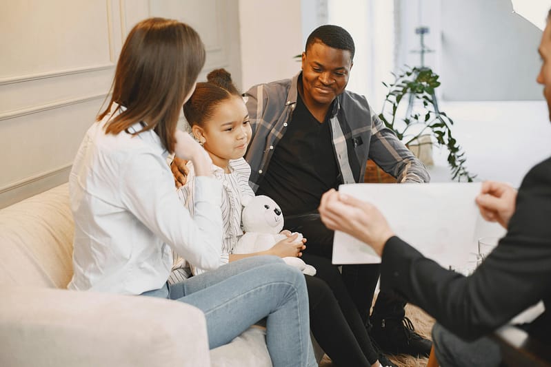 A family with a young daughter attending a counseling session with a therapist