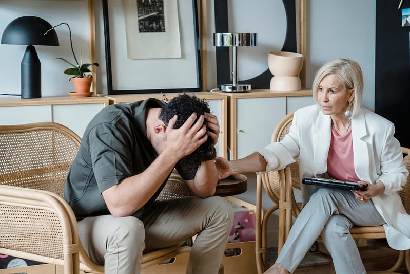 A therapist offering comfort to a distressed young man during a counseling session